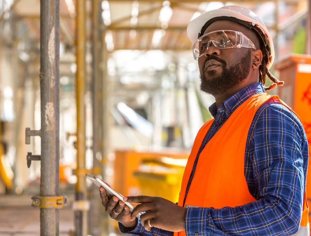 Construction worker on an active job site surrounded by equipment and scaffolding, illustrating the common hazards and causes of construction site accidents.