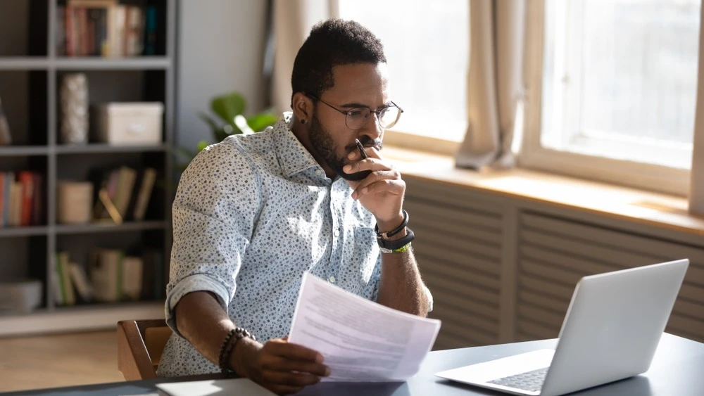 Person working on a laptop while reviewing documents and records, illustrating the process of evaluating compensation for a Brownsville whiplash injury claim.