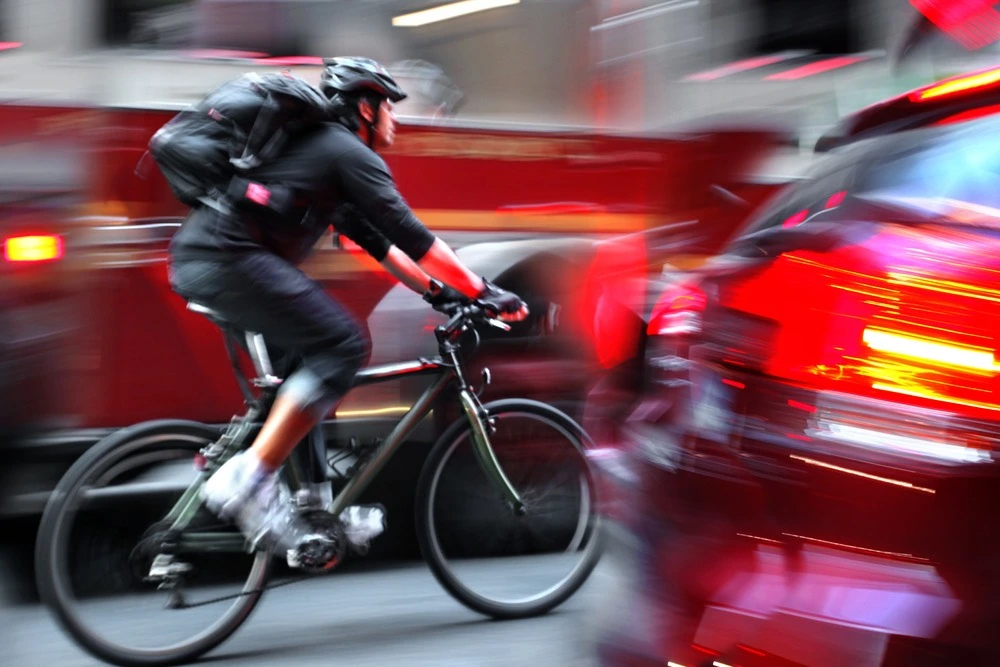 Cyclist riding through heavy traffic on a busy roadway, illustrating how bicycle accidents happen in Harlingen.