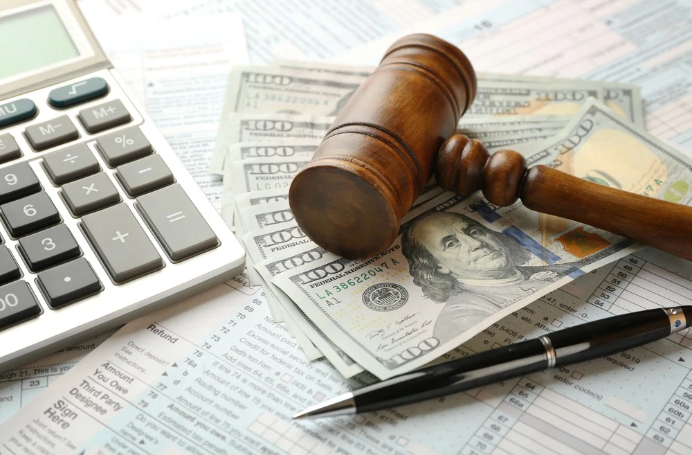 Courtroom gavel set on legal and financial documents with a calculator and cash nearby, illustrating the damages you may recover in Harlingen traumatic brain injury cases.