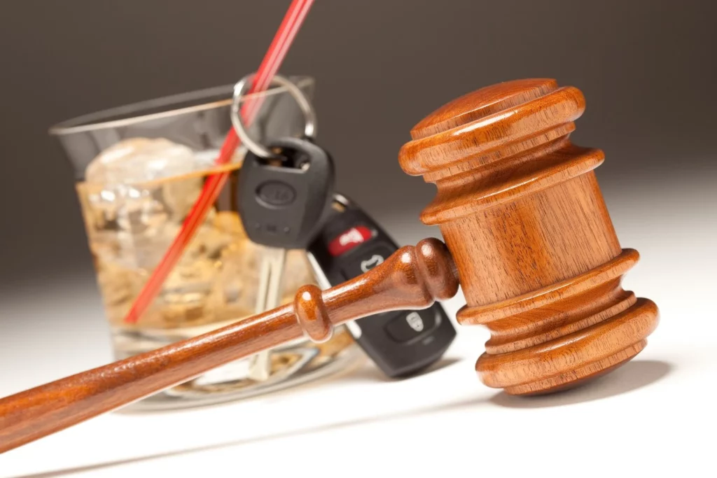 Un mazo de tribunal junto a una bebida alcohólica y unas llaves de coche, que ilustran las leyes de Texas sobre la responsabilidad de los establecimientos que sirven alcohol y la responsabilidad de los bares.