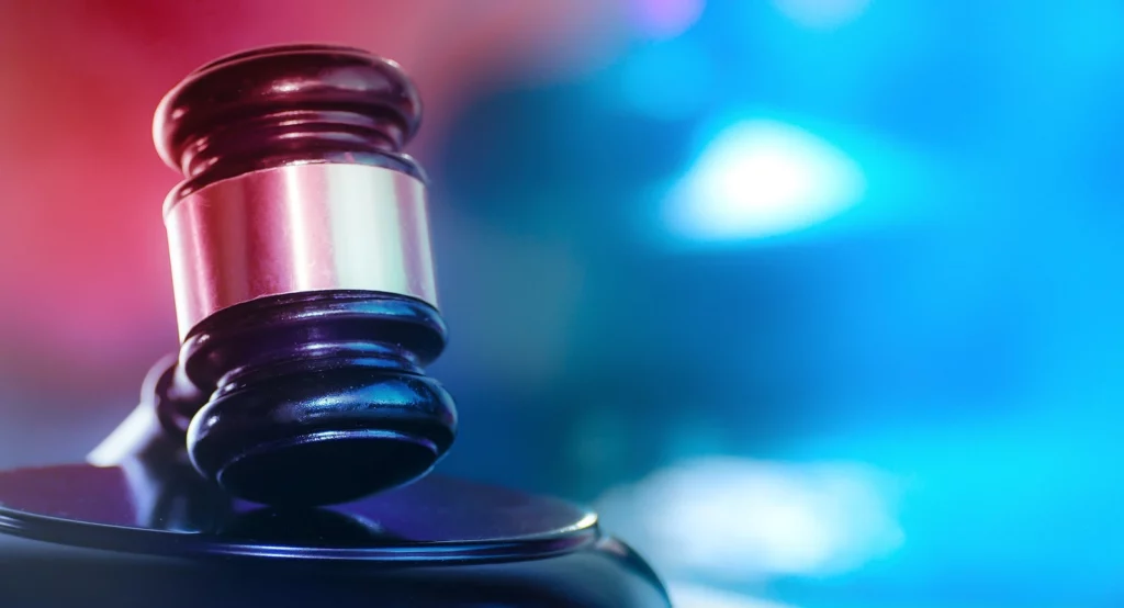 Courtroom gavel beside flashing police lights, illustrating Texas hit and run laws and the penalties drivers may face.