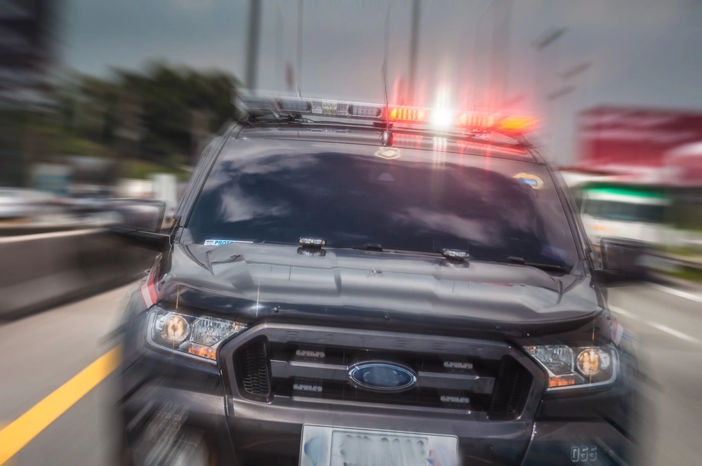 Vehicle speeding away from a roadway scene as police lights flash nearby, illustrating hit-and-run accidents in McAllen.