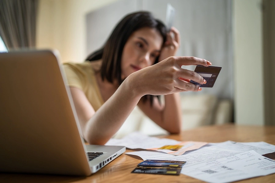 Person behind a laptop reviewing bills, documents, and credit cards, illustrating the compensation that can be recovered after a McAllen pedestrian accident.