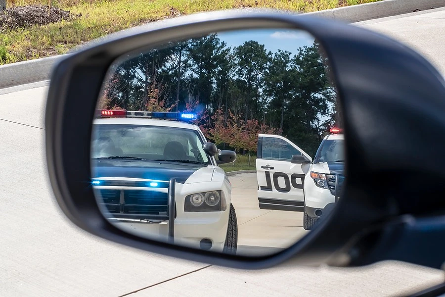 Police cars with flashing lights reflected in a side view mirror, illustrating international bridge accidents in the Rio Grande Valley.