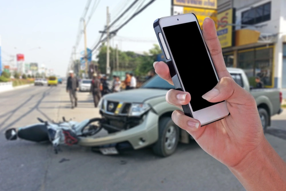Person taking photos of a damaged vehicle at an accident scene, illustrating what to do after an accident in Mercedes, Texas.